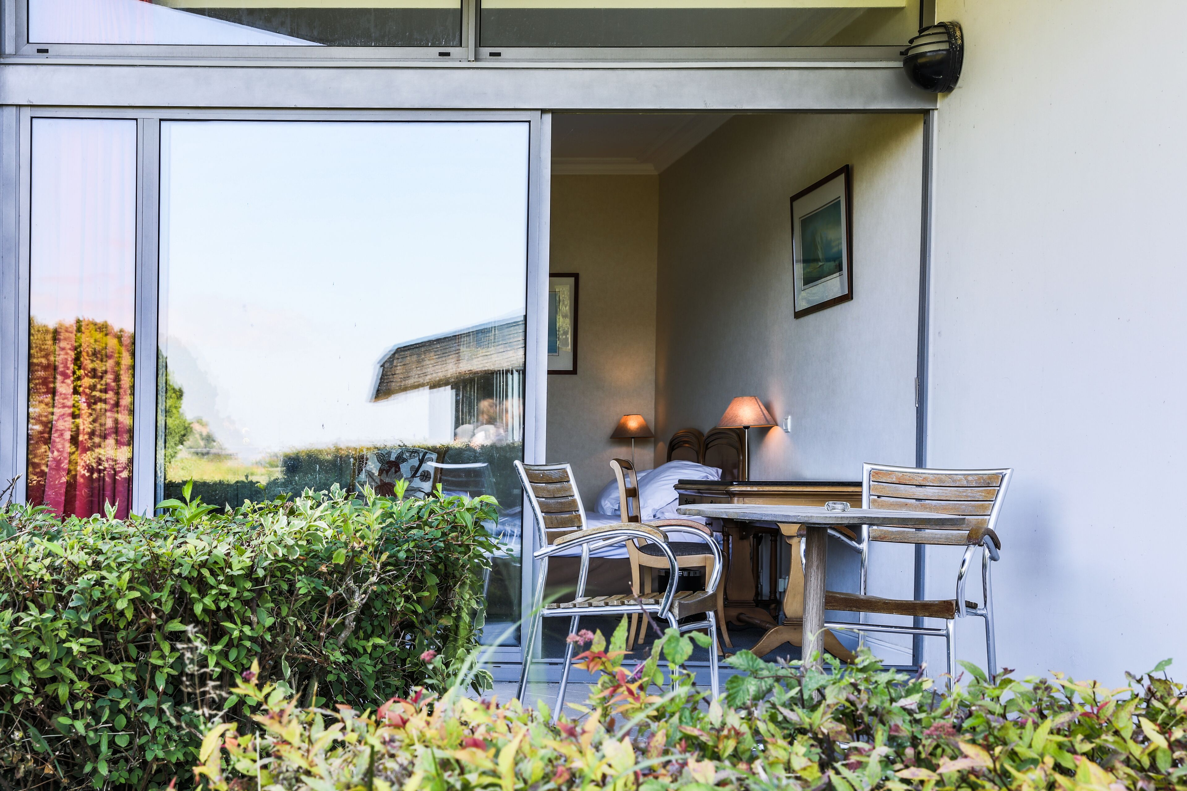 Un espace extérieur aménagé avec une table et des chaises, une lampe et un tableau encadré accroché au mur.