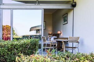 Un área de estar al aire libre con una mesa, sillas, una lámpara y un cuadro en la pared.