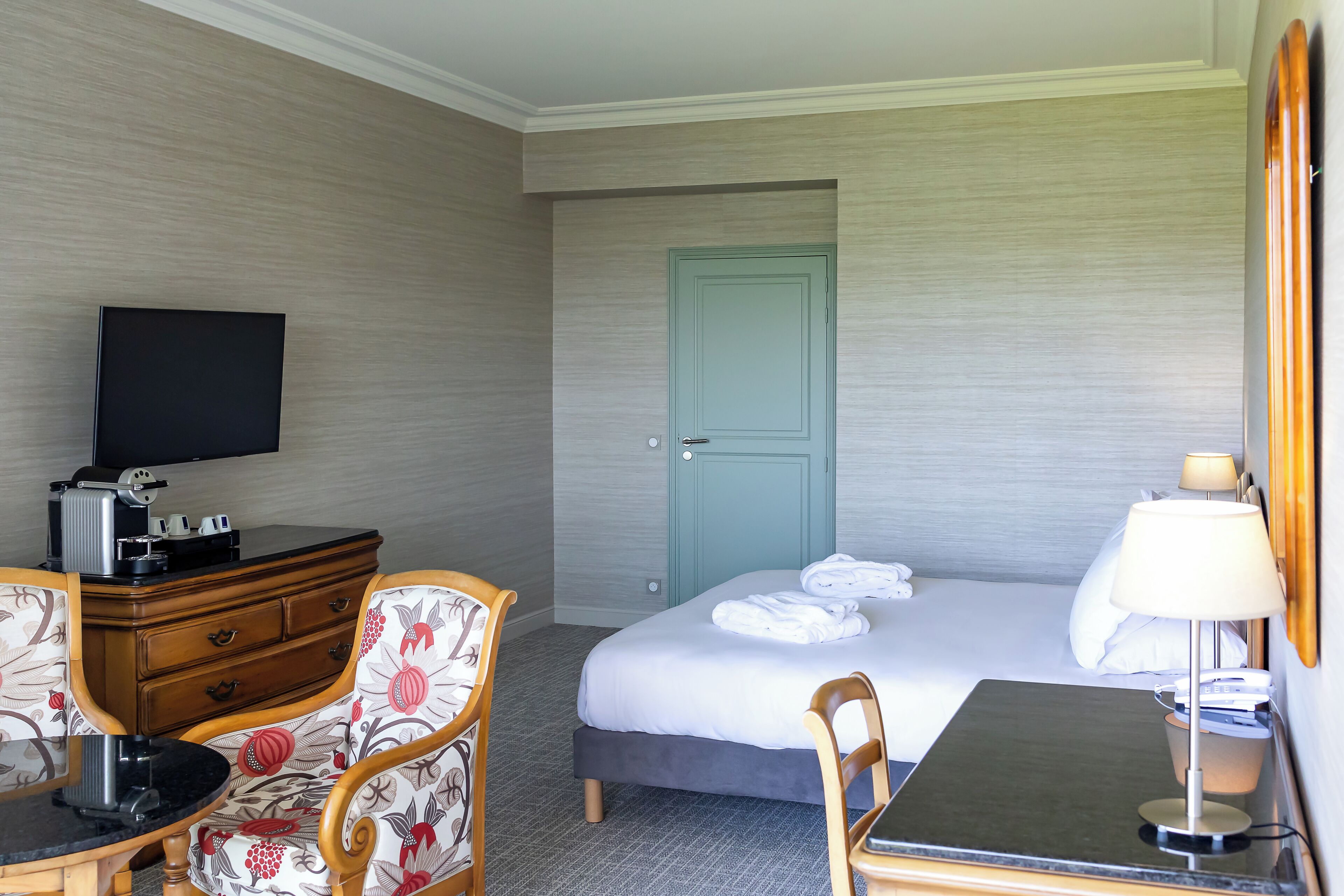 Une chambre d’hôtel comprenant un lit, un bureau, une chaise, une télévision et une commode.