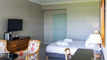 Une chambre d’hôtel comprenant un lit, un bureau, une chaise, une télévision et une commode.