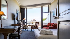 Habitación de hotel con cama, escritorio, sillas y vistas a un monumento lejano.