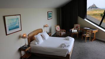 Ein Hotelzimmer mit einem Bett, zwei Stühlen, einem Schreibtisch und Blick auf ein Schloss.