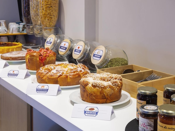 A bakery display with various baked goods and jars of preserves. - Greet Hotel Nancy Sud (Houdemont)