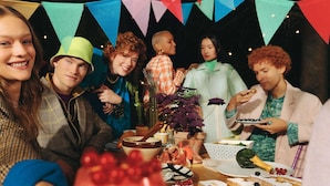 Un grupo de personas en una fiesta, con una mesa repleta de comida y bebidas.