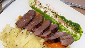 Un plato de comida con carne en rodajas, verduras y salsa verde.