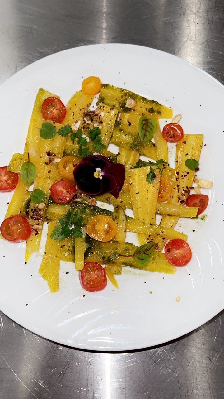 Lautasella on pastaa, kirsikkatomaatteja ja koristeeksi jotain.