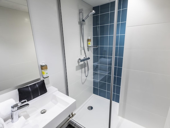 A bathroom with a white sink, a handheld showerhead, and a glass-enclosed shower.