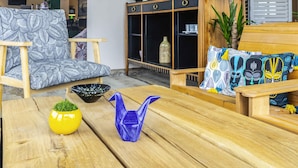 Un sofá de madera con cojines estampados, una mesa de madera con objetos decorativos y una estantería con diversos objetos.