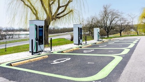 Estaciones de carga para vehículos eléctricos, un carril bici y una zona arbolada.
