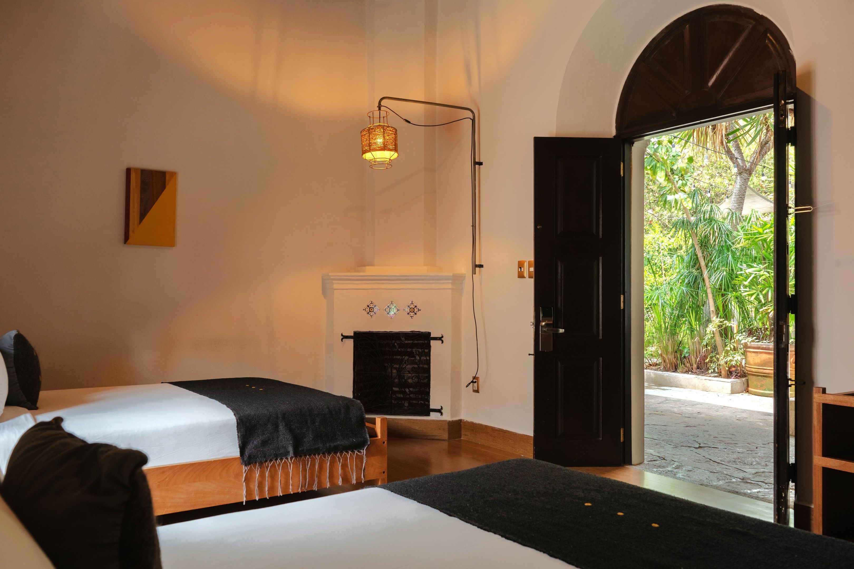 A hotel room with two beds, a fireplace, and a view of greenery outside.