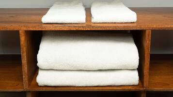 A wooden shelf with three folded white towels.