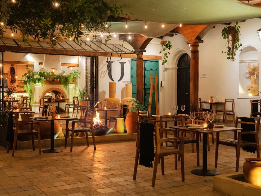 An outdoor dining area with tables and chairs, a fire feature, and hanging plants.