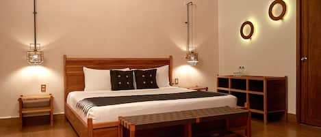 A neatly arranged bedroom with a wooden bed, bedside tables, a bench, and wall-mounted lighting fixtures.