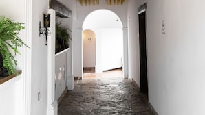 A hallway with stone flooring, white walls, and wooden beams. - Hotel Sombra del Agua (San Cristóbal de las Casas)