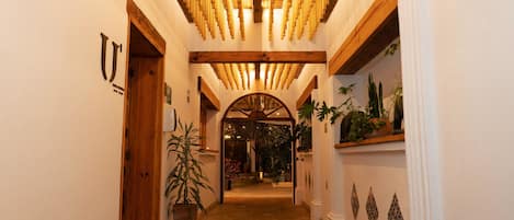 Un pasillo con vigas de madera, una puerta de madera y plantas en macetas.