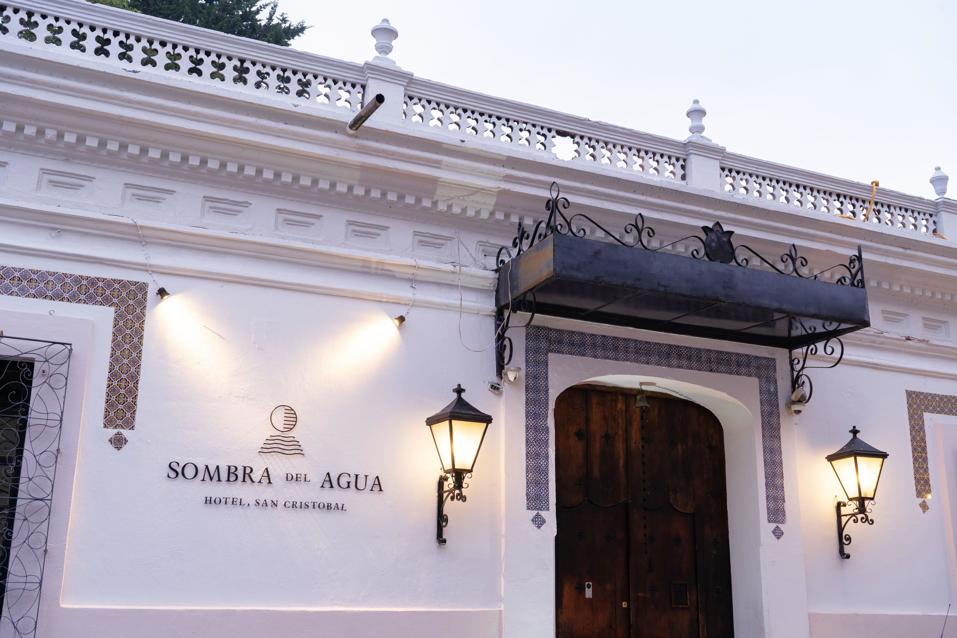 Fachada exterior del Hotel Sombra del Agua, con diseño tradicional, detalles de metal ornamentado y una gran puerta de madera.