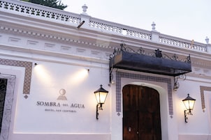 Fachada exterior del Hotel Sombra del Agua, con diseño tradicional, detalles de metal ornamentado y una gran puerta de madera.