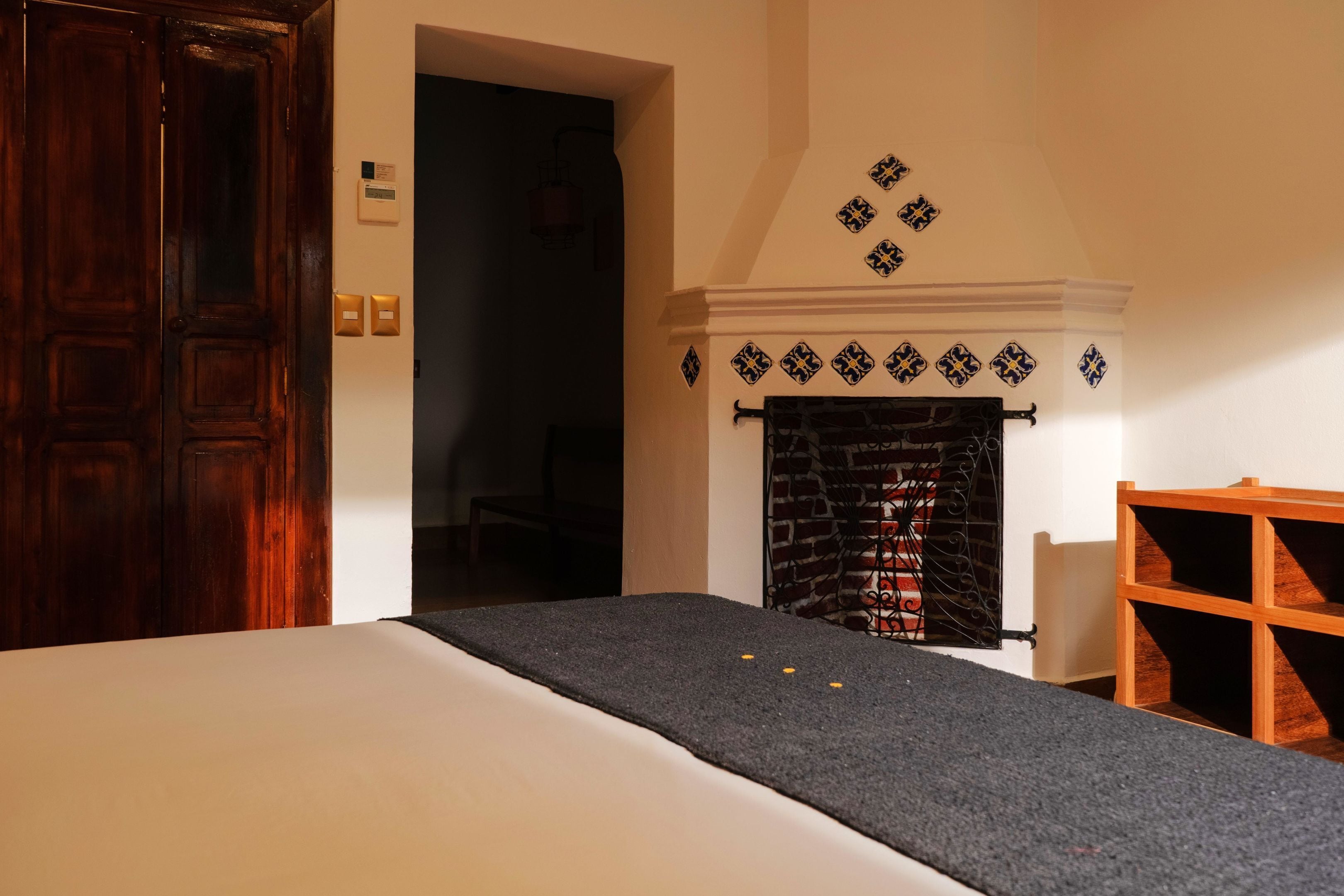 Une pièce avec un lit, une cheminée et une porte en bois.