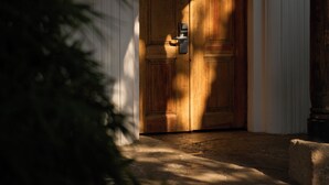 A wooden door with a keyhole, set in a white-walled room with an arched doorway. - Hotel Sombra del Agua (San Cristóbal de las Casas)