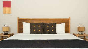 A neatly made bed with a wooden headboard, two bedside lamps, and a black throw blanket.