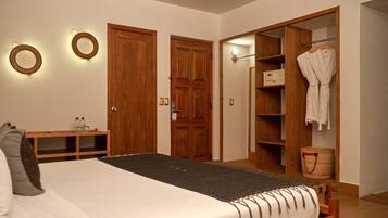 A bedroom with a bed, bedside table, wooden wardrobe, and a bathroom with a towel rack.