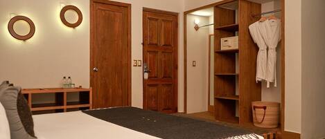 A bedroom with a bed, bedside table, wooden wardrobe, and a bathroom with a towel rack.