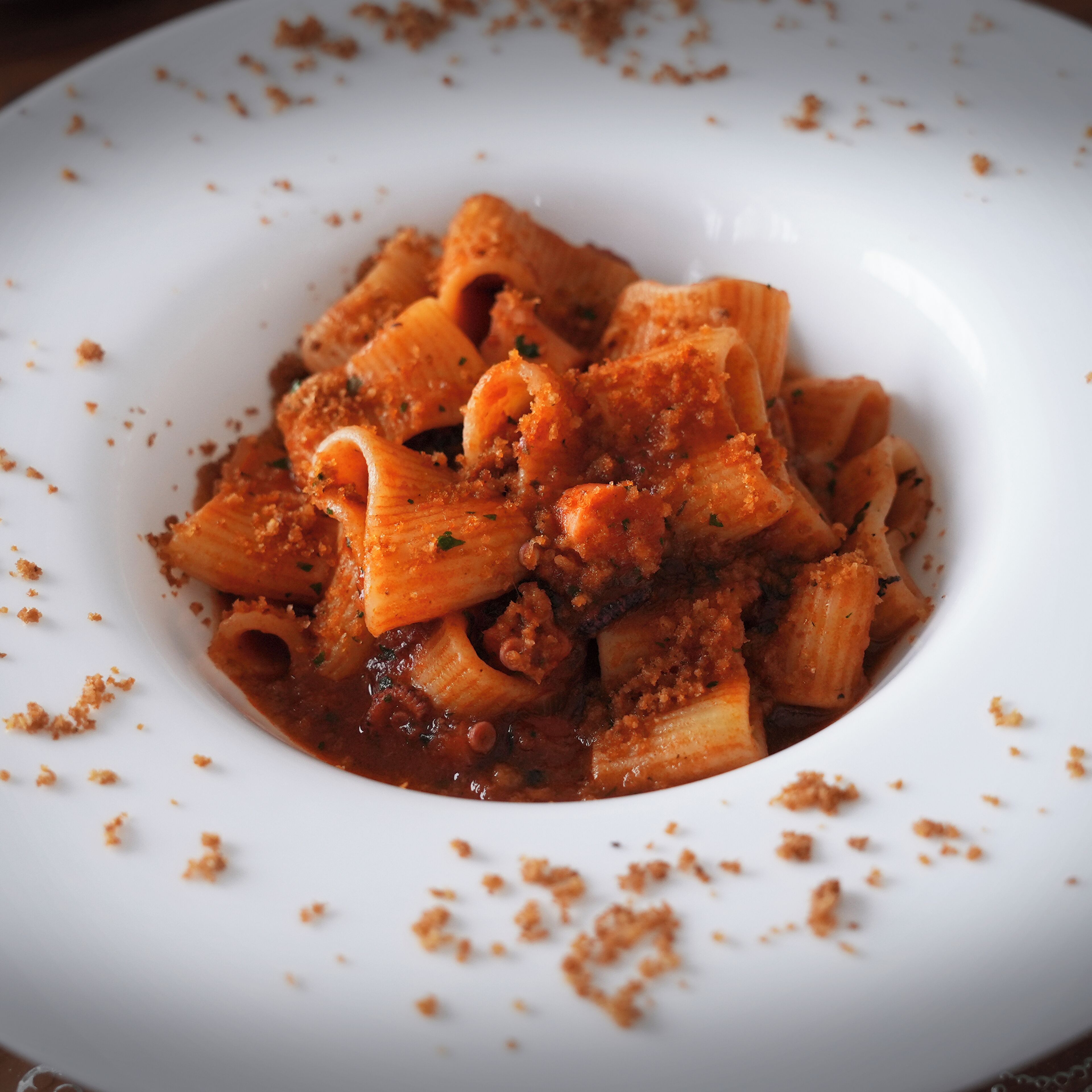 Lautasella on pastaa, tomaattipohjaista kastiketta ja jauhelihaa, ja annos on koristeltu yrteillä.