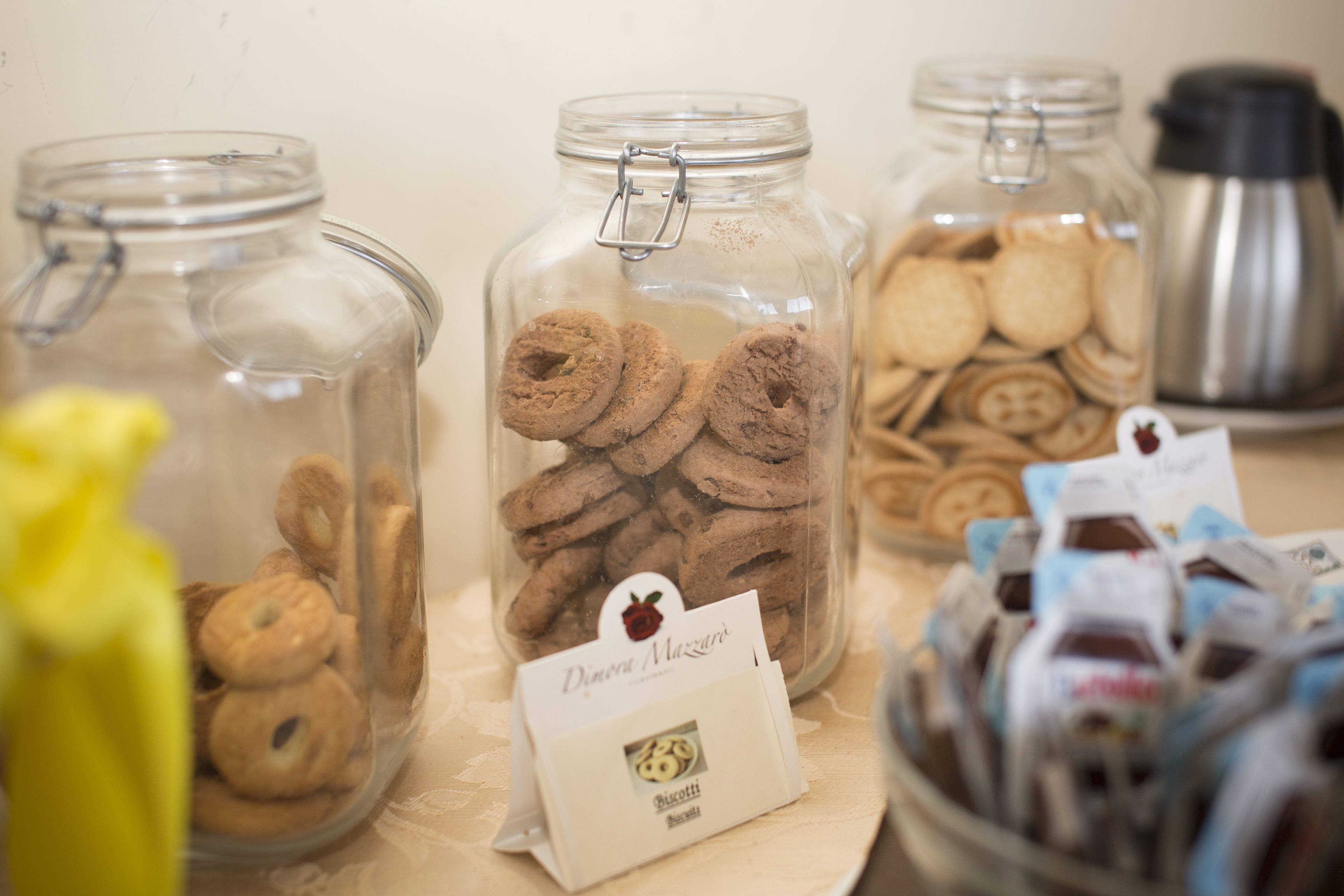 Three glass jars filled with cookies, each labeled with a name and a logo.