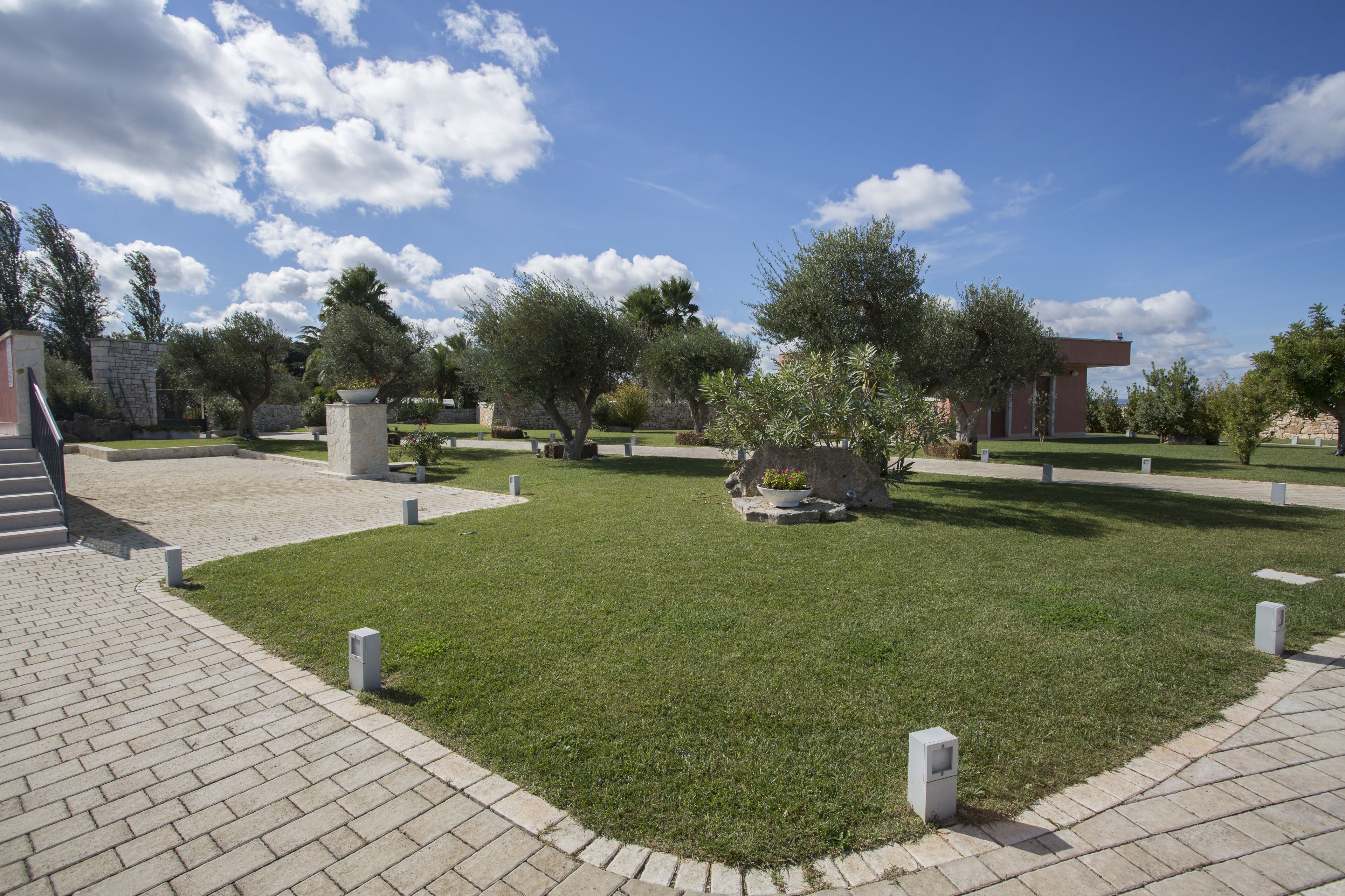 A courtyard with a paved walkway, stone benches, and a variety of trees.