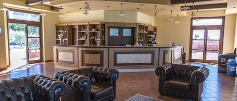 A spacious living area with leather sofas, a large rug, and a kitchen area with cabinets and a bar.