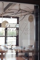 A breakfast room with a glass wall, wooden beams, and hanging decorations.