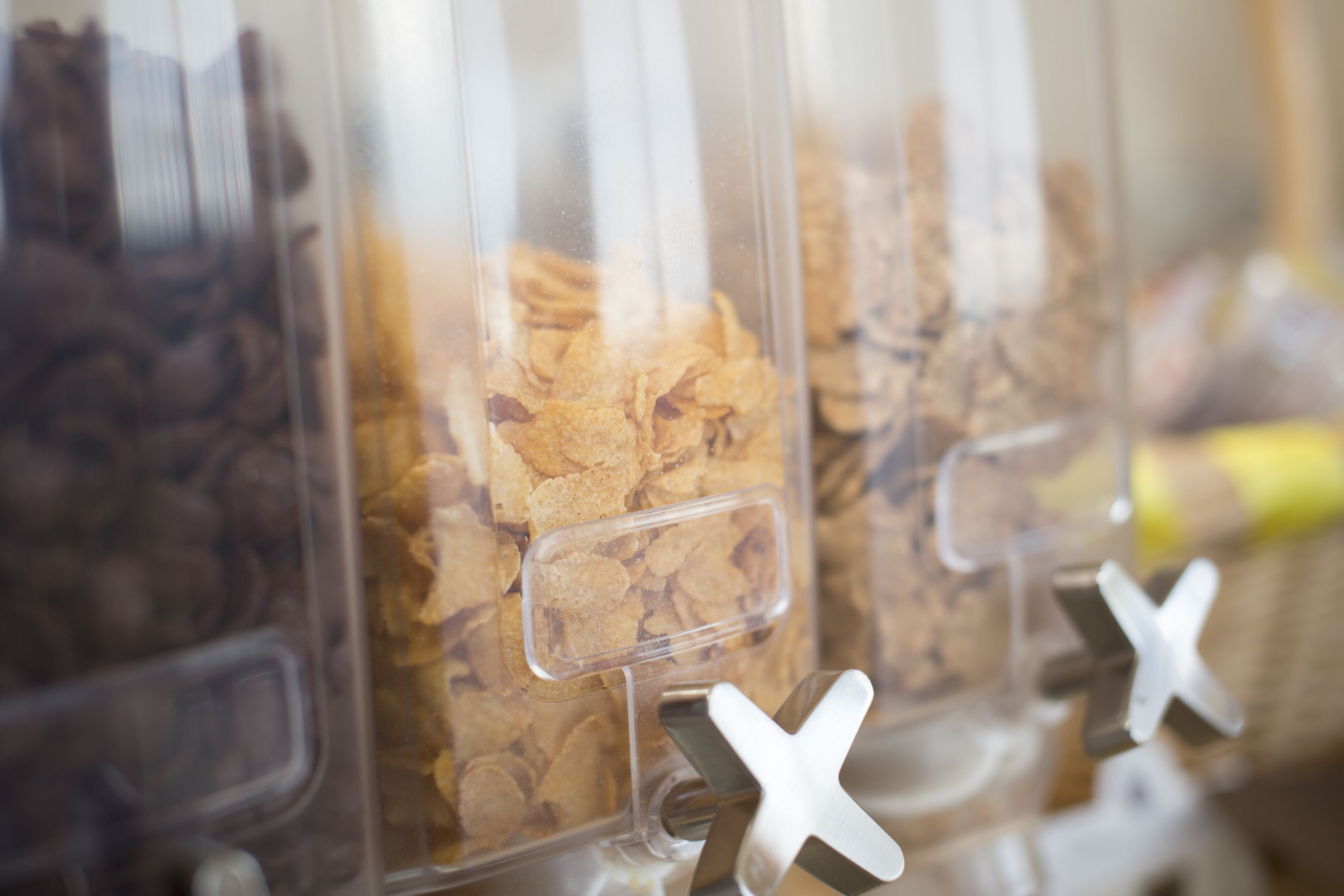 A row of cereal containers with a clear divider and a metal 'X' mark on each.