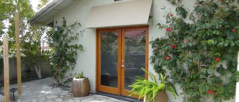 A house with a stone patio, a wooden door, and potted plants.