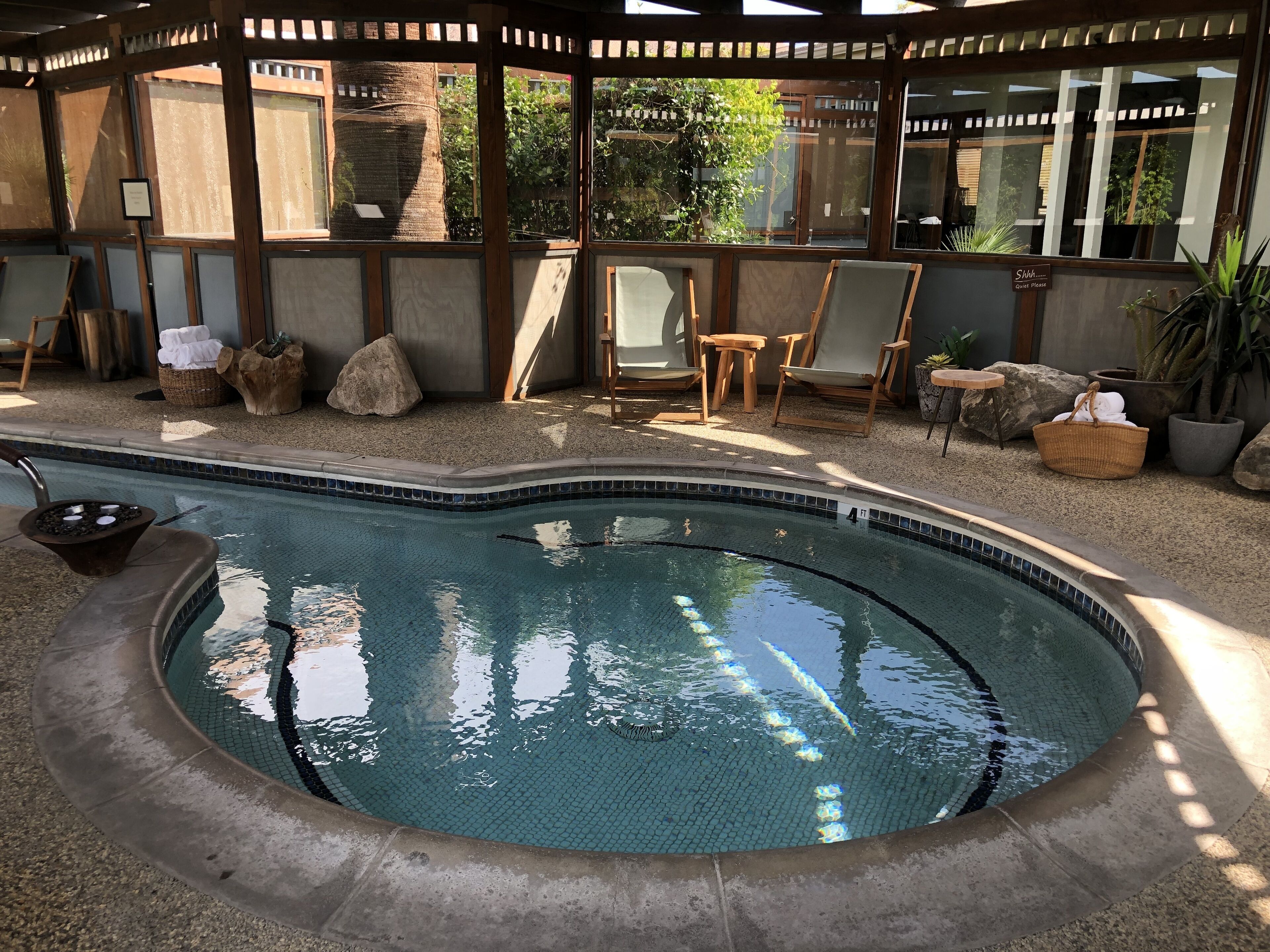 A hot tub with a tiled edge, surrounded by outdoor seating and plants.