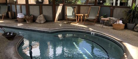 A hot tub with a tiled edge, surrounded by outdoor seating and plants.