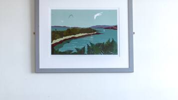 Relax in a serene space with a comfortable bed, a beautiful coastal artwork above, and a clean, minimalist design.