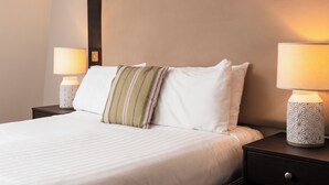 A neatly made bed with white linens, a striped pillow, and two bedside lamps with geometric patterns. - Kings Arms Hotel (Kyleakin)