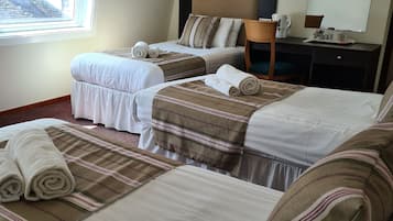 A hotel room with two beds, a desk, a chair, a coffee maker, and a large window.