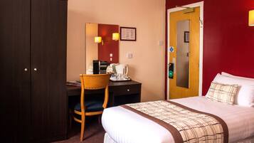 Habitación de hotel con cama, escritorio, silla, armario y puerta con espejo.