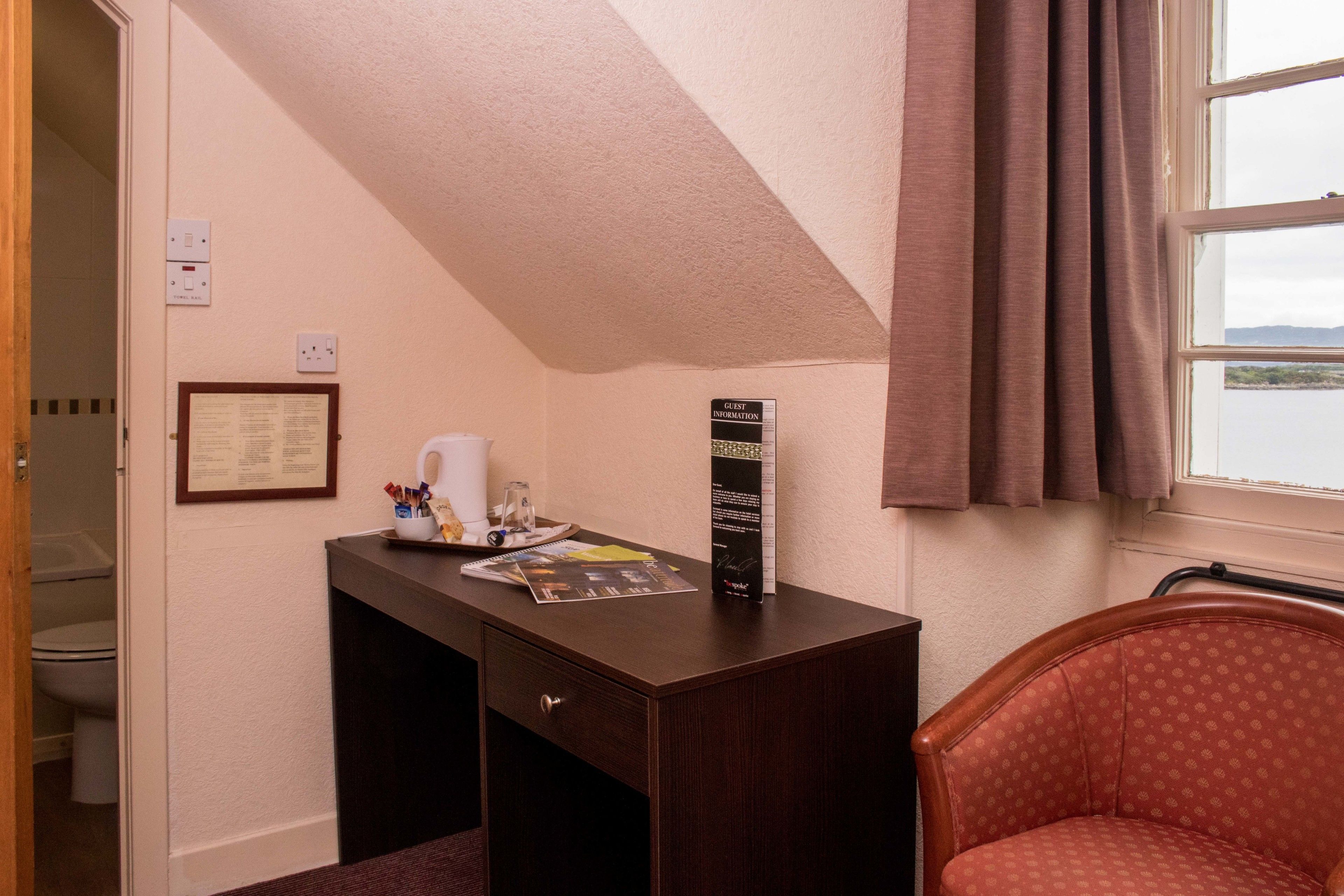 A small, private office with a desk, chair, and a window with curtains.