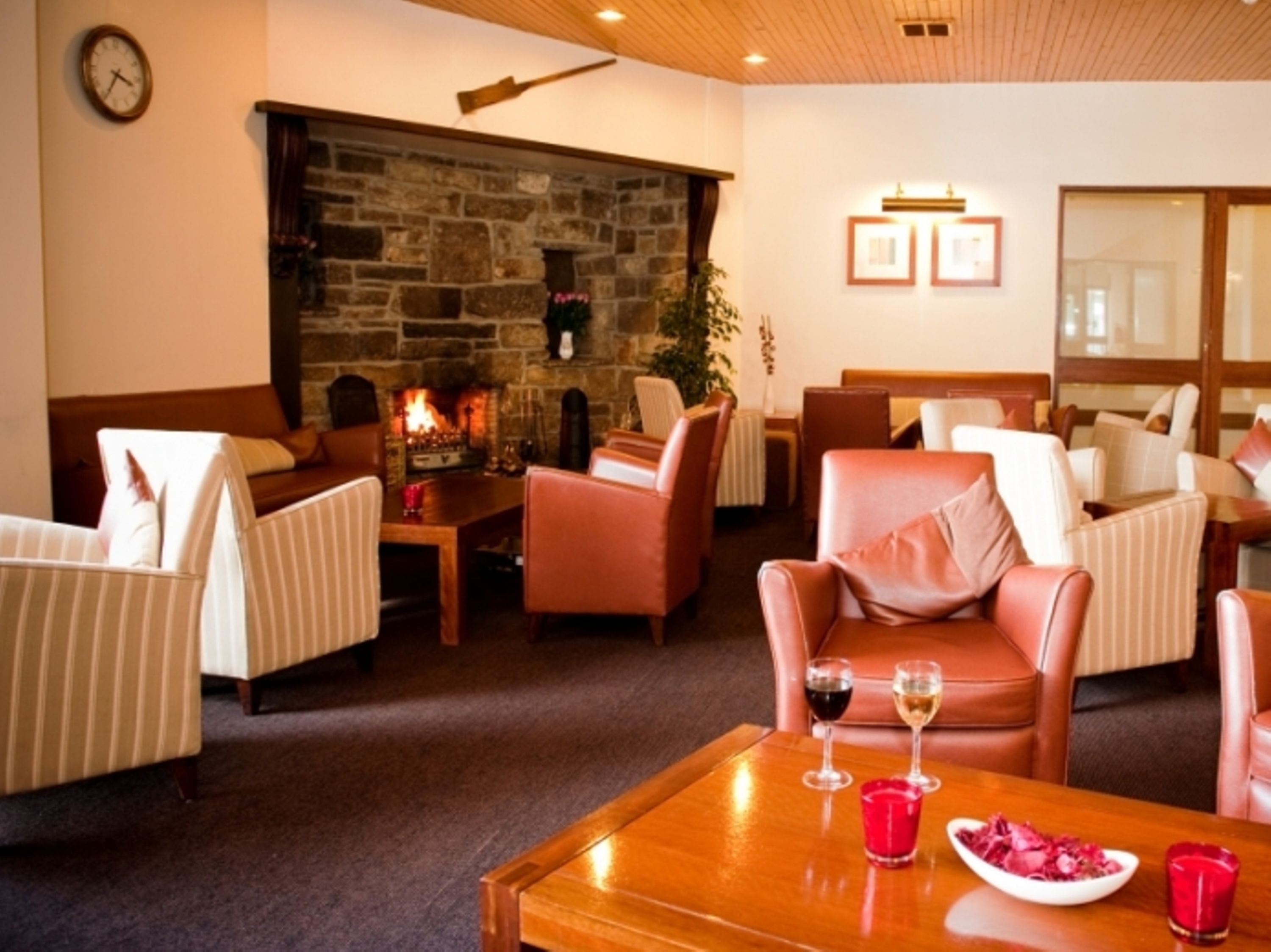 A cozy lounge area with leather sofas, a wooden coffee table, and a stone fireplace.