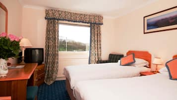 A hotel room with two beds, a desk with a television, a window with curtains, and a painting on the wall.