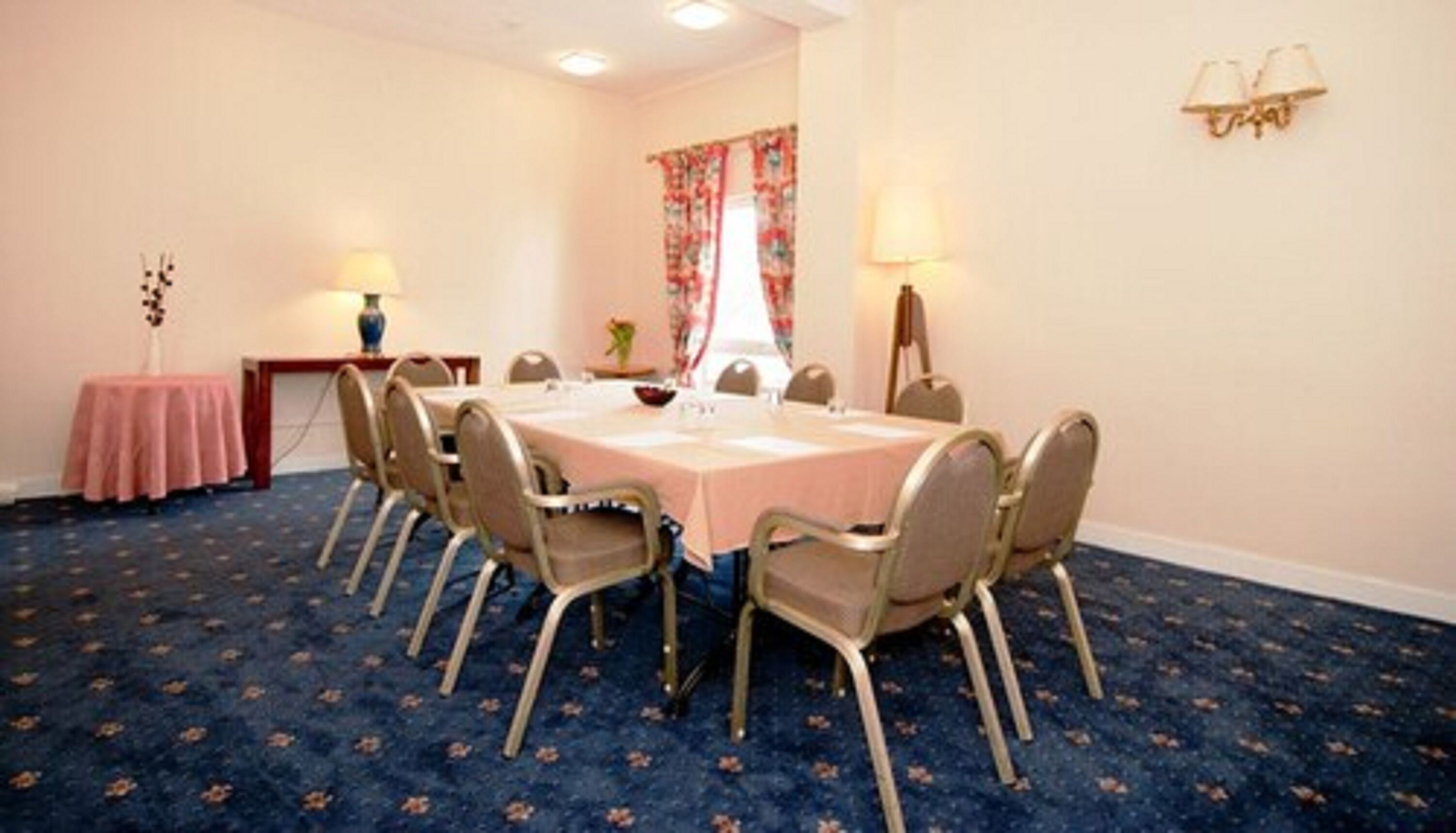 A conference room with a round table, chairs, a small side table, and lamps.