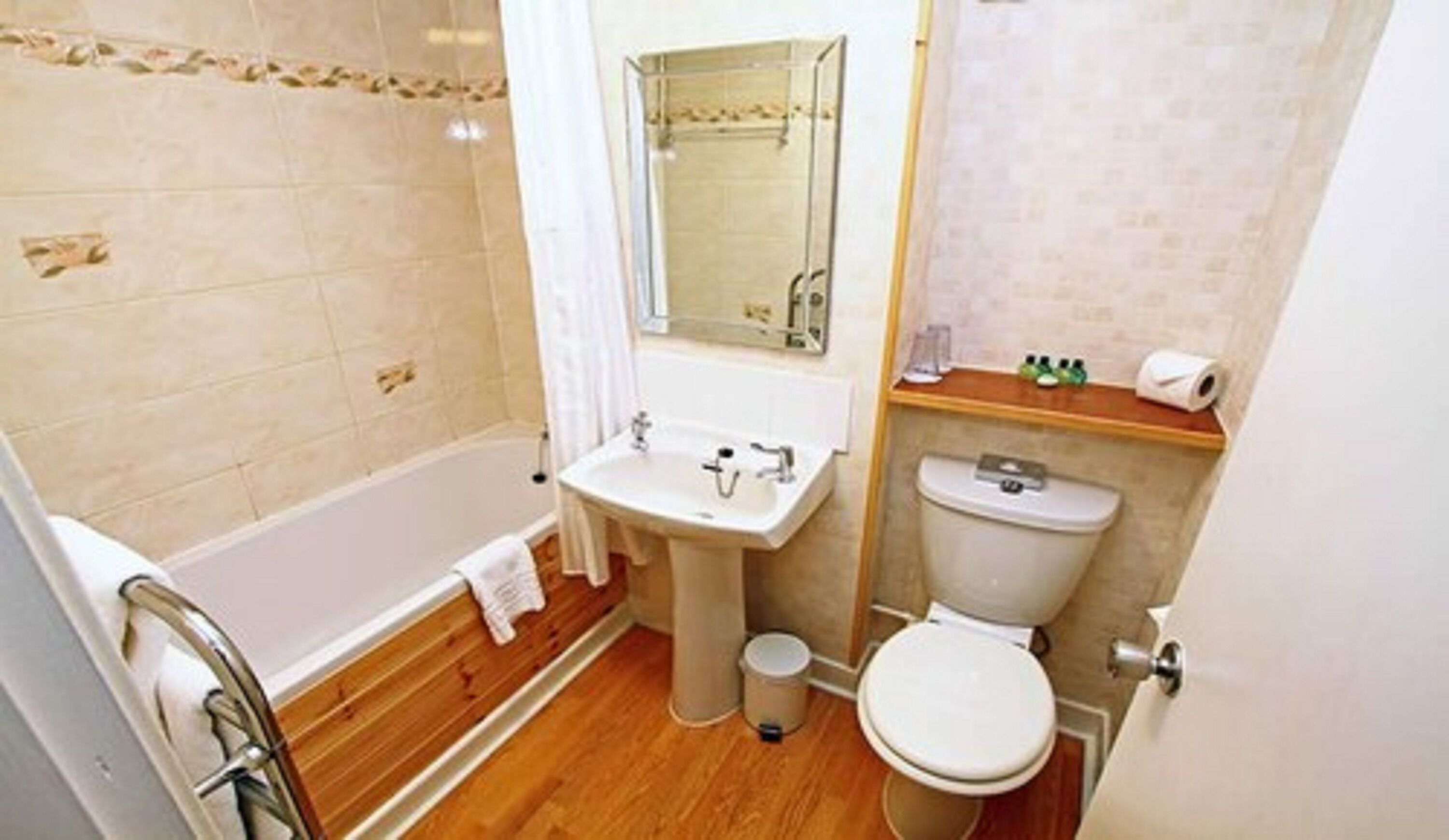 A bathroom with a bathtub, sink, toilet, and a mirror.