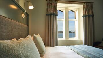 A neatly made bed with patterned pillows, a headboard, and a window with curtains.