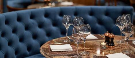 A round table with a marble top, surrounded by a plush blue upholstered sofa.