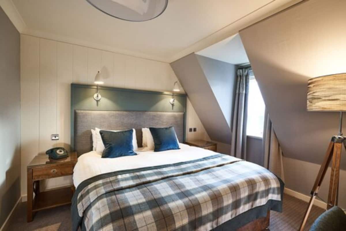 A bedroom with a bed, nightstands, a lamp, and a window.