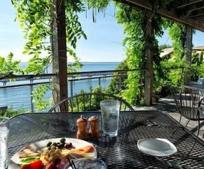 Una mesa con comida, un vaso de agua y saleros y pimenteros, con vista a un cuerpo de agua.