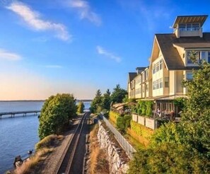 A coastal property with a long driveway leading to a house with multiple levels and large windows.