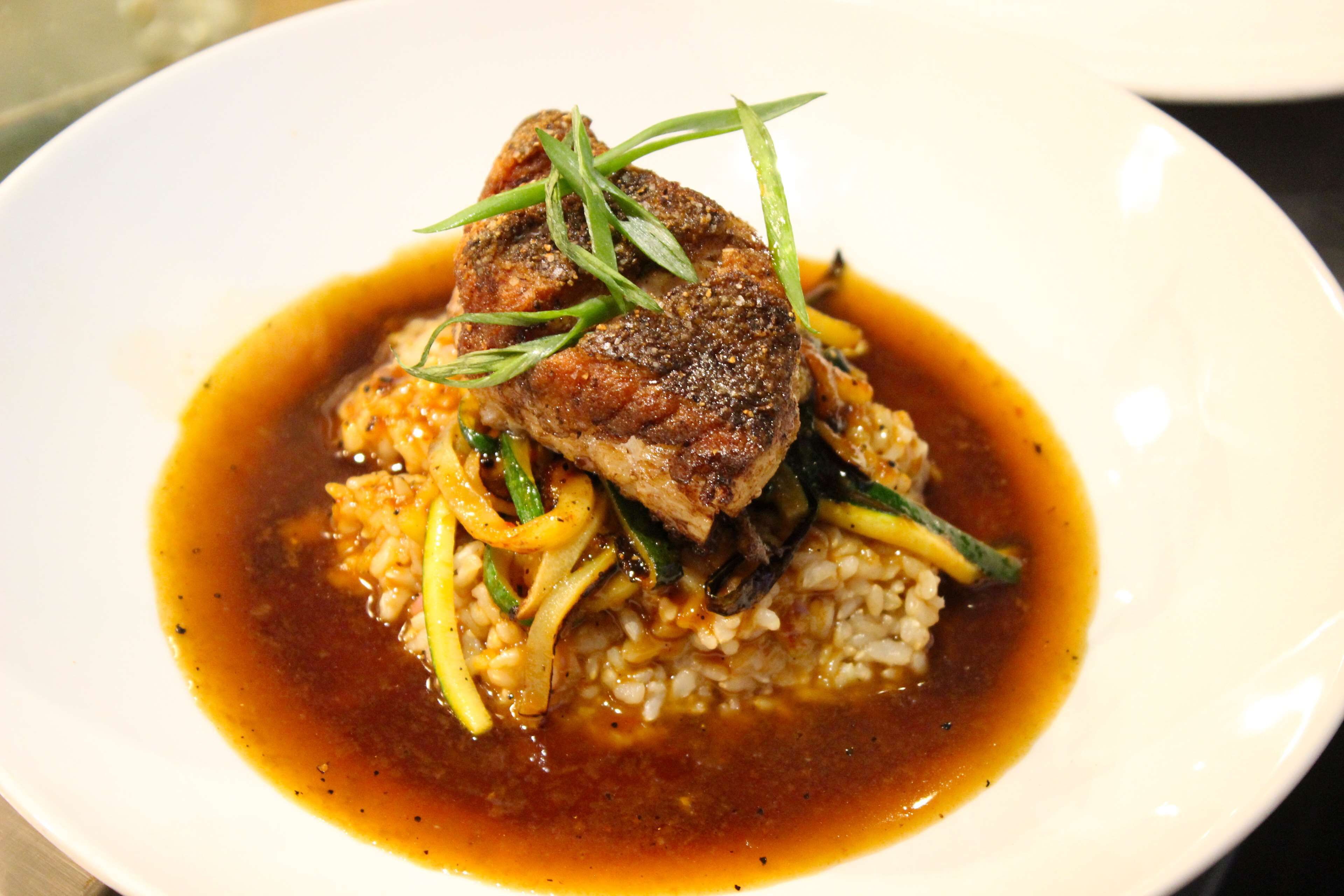 A plate of food with a piece of meat, vegetables, and rice.